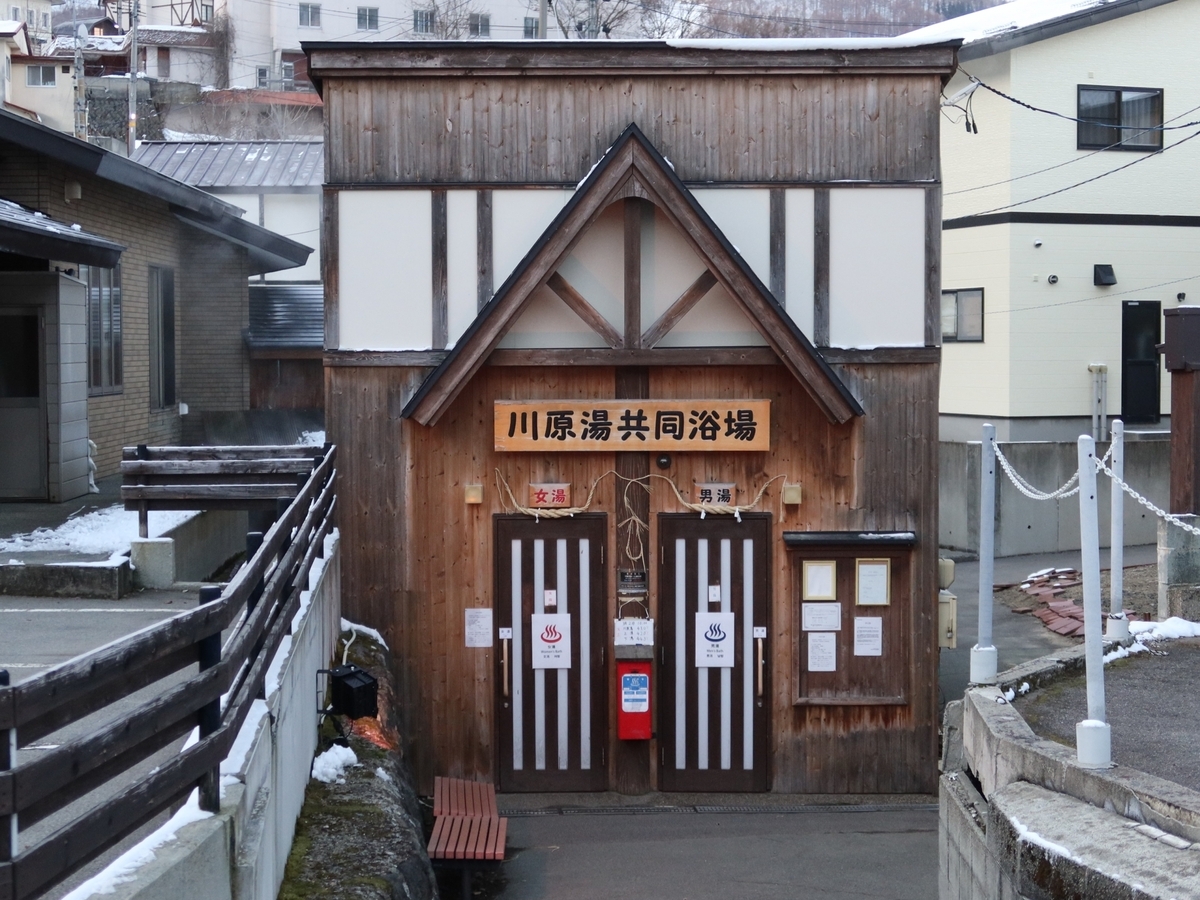 殘雪未消的溫泉街中矗立的木造共同浴場