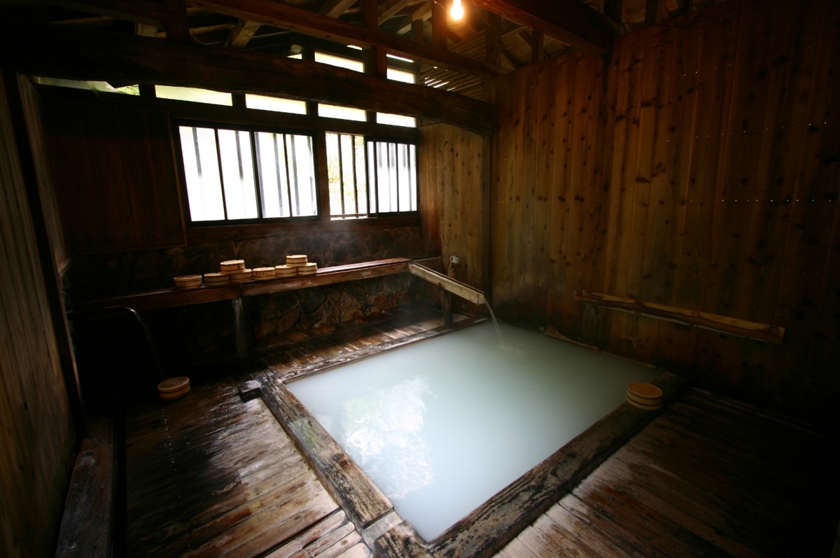 木造浴室中盛滿白濁湯水的內湯