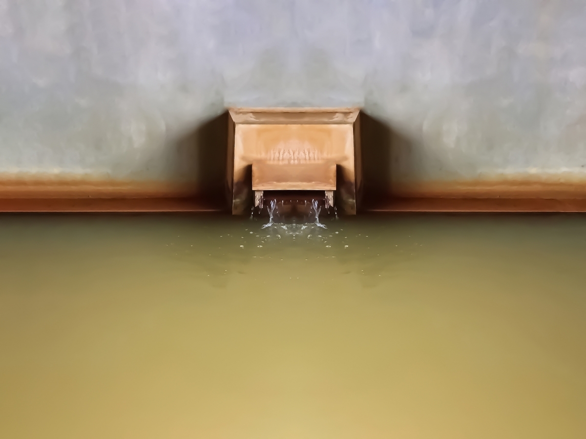 Yellow-green hot spring water pouring from the spout into a bathtub