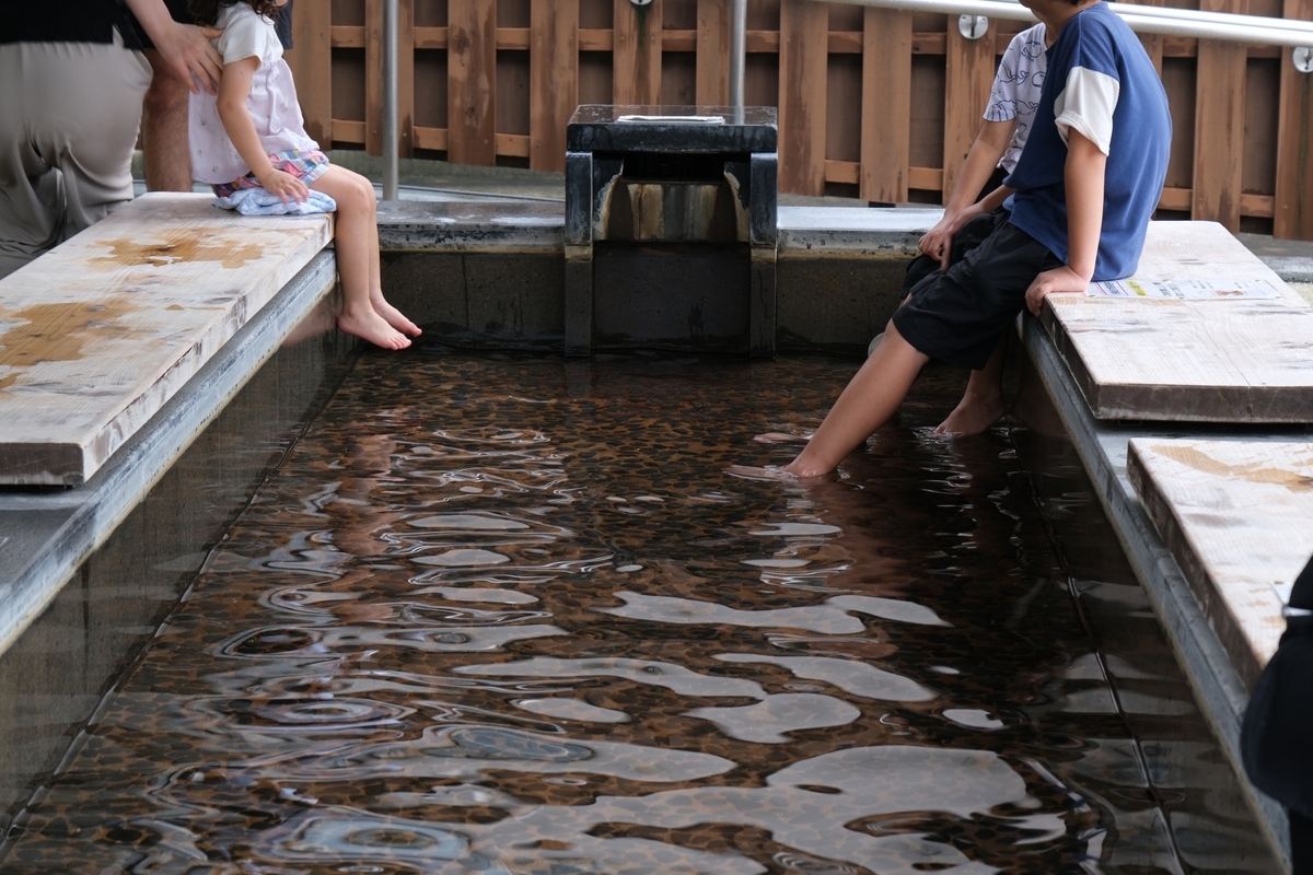Foot bath enclosed in wood, with people dipping their feet in the water