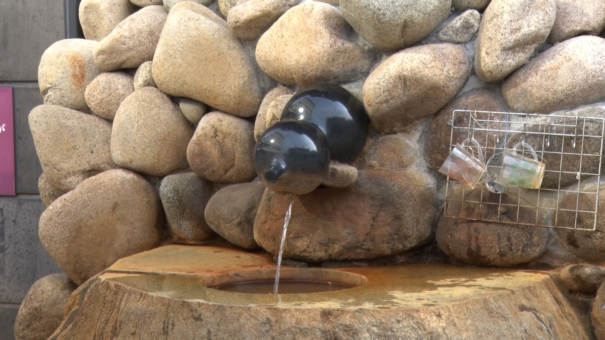 Stone wall spout for drinking spring water, with a ladle stand nearby