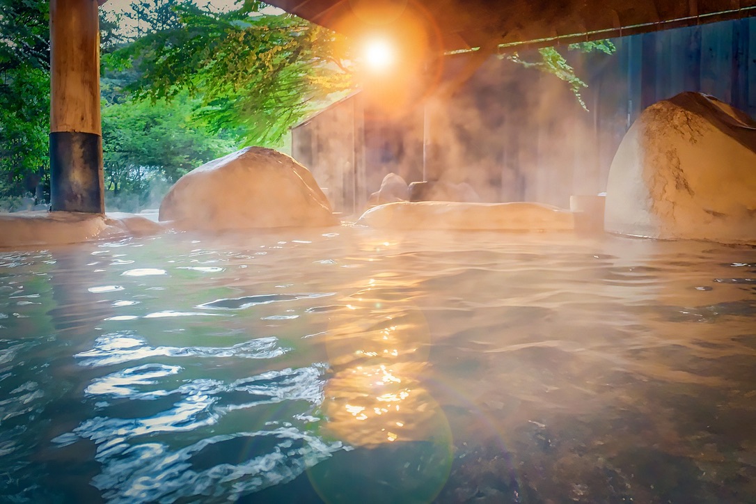 Sunset light filtering through the steam of an open-air bath