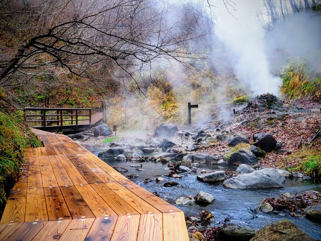 Una fuente termal natural humeando junto a una pasarela de madera