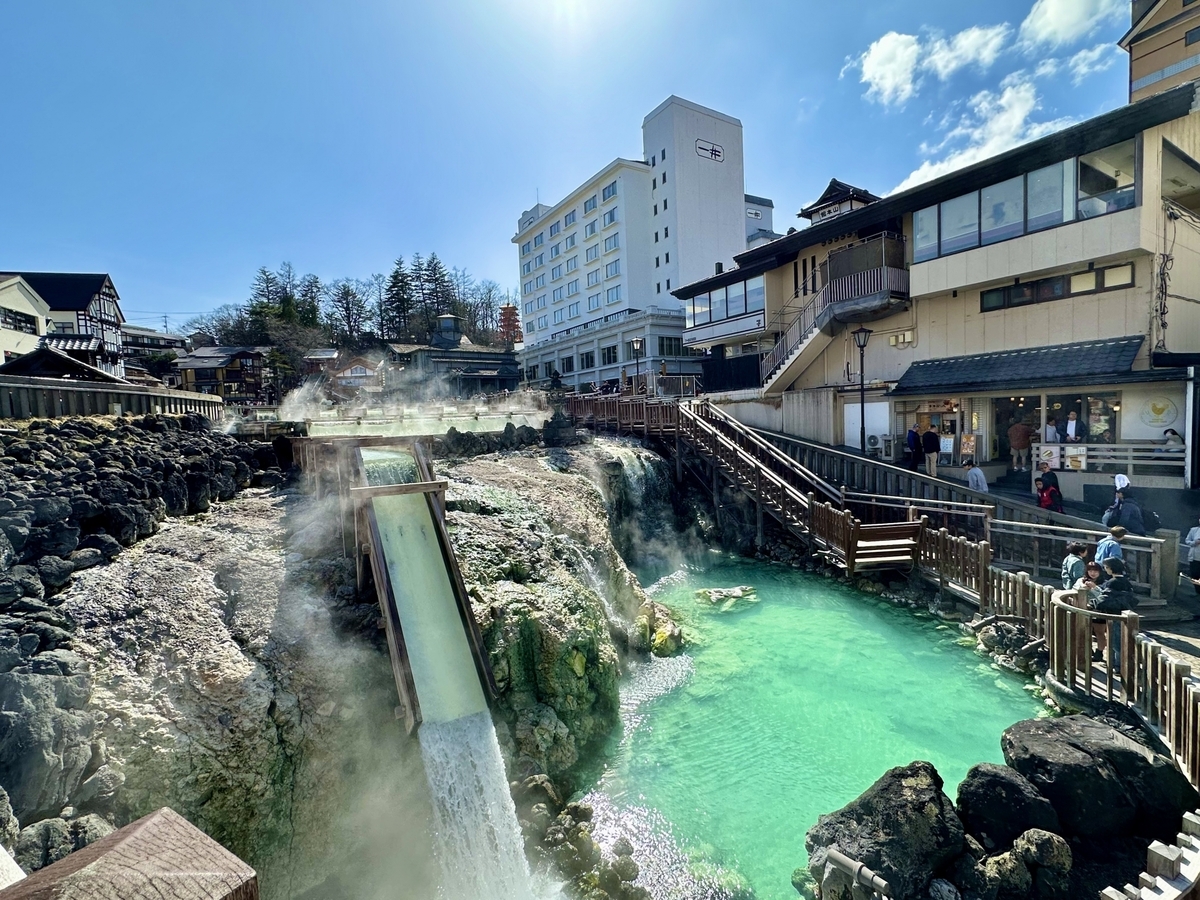 El agua de manantial de un blanco lechoso fluyendo por el yubatake de Kusatsu Onsen y el pueblo circundante