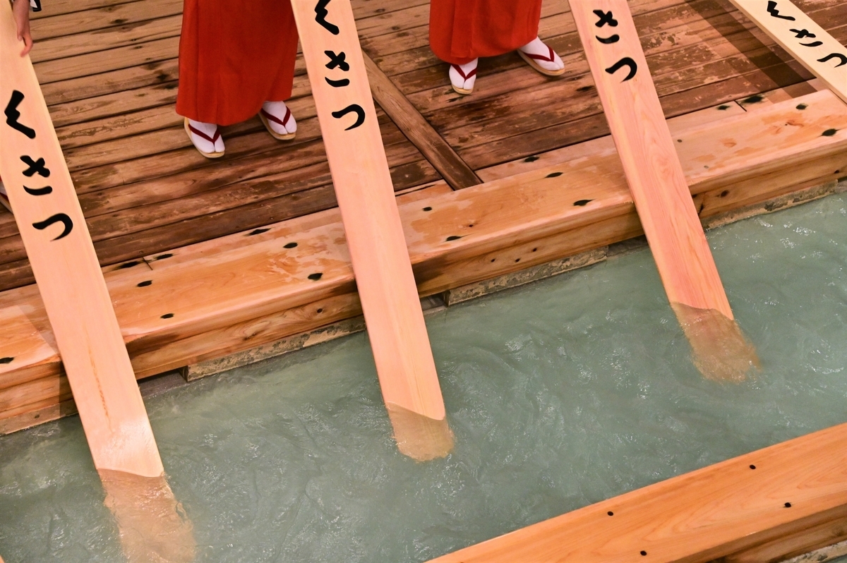 Paletas de madera siendo introducidas en el agua durante el yumomi de Kusatsu Onsen