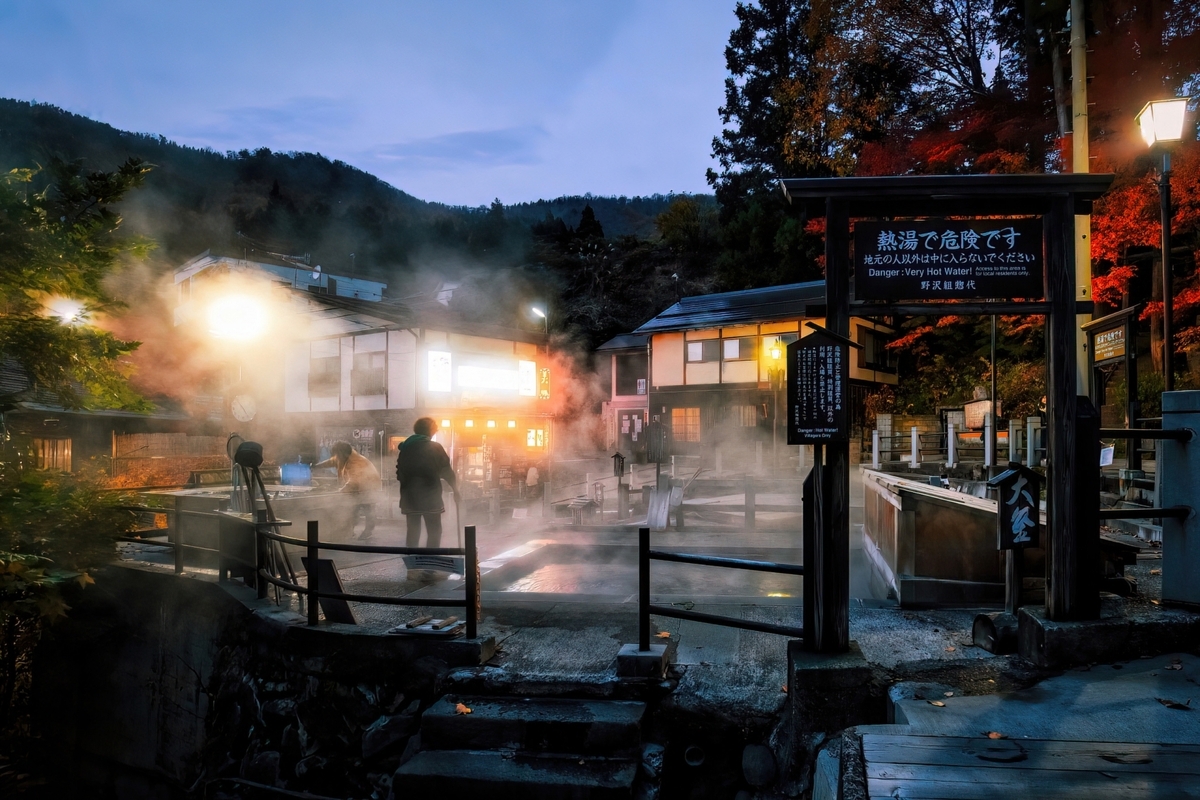 Vapor elevándose desde la fuente termal Ogama de Nozawa Onsen al anochecer
