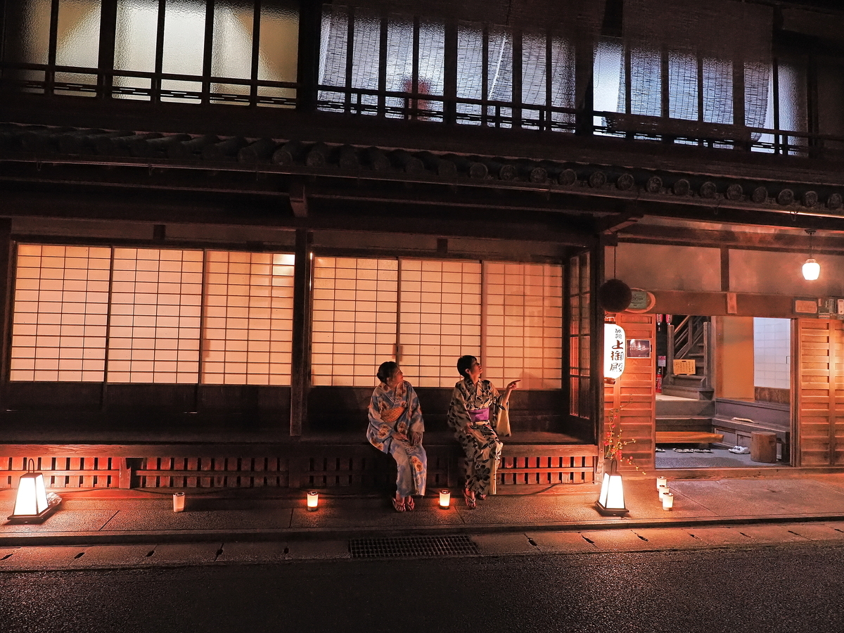 Una persona en yukata sentada frente a una posada en Ryujin Onsen de noche