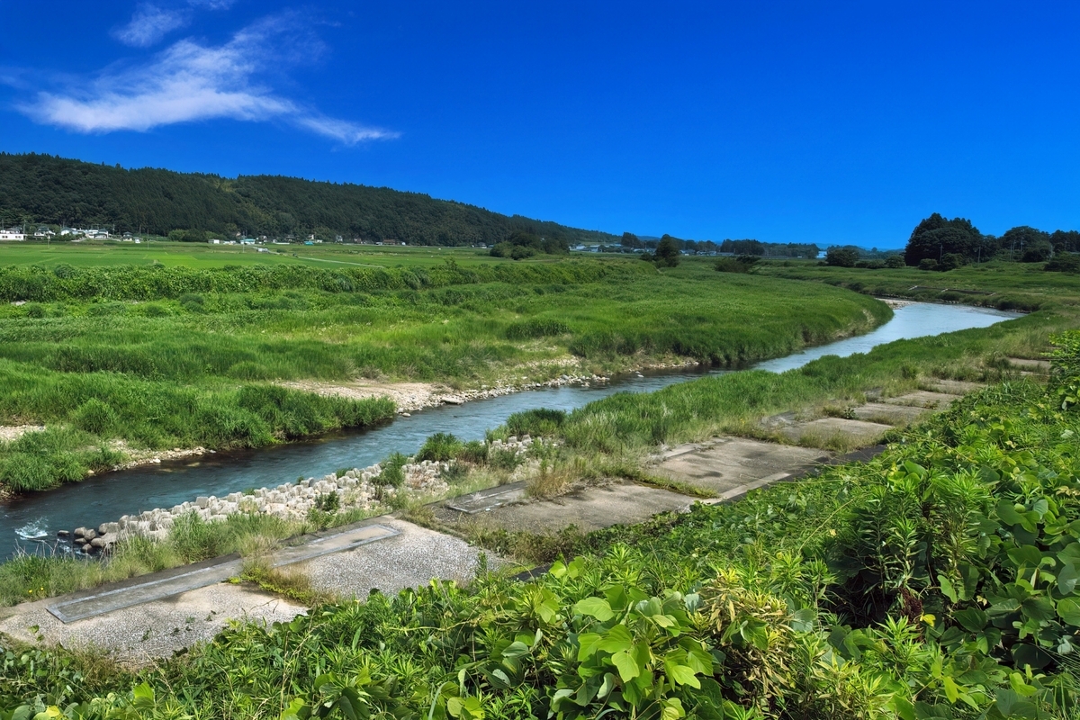 Un río que fluye cerca de Kitsuregawa Onsen y verdes campos rurales