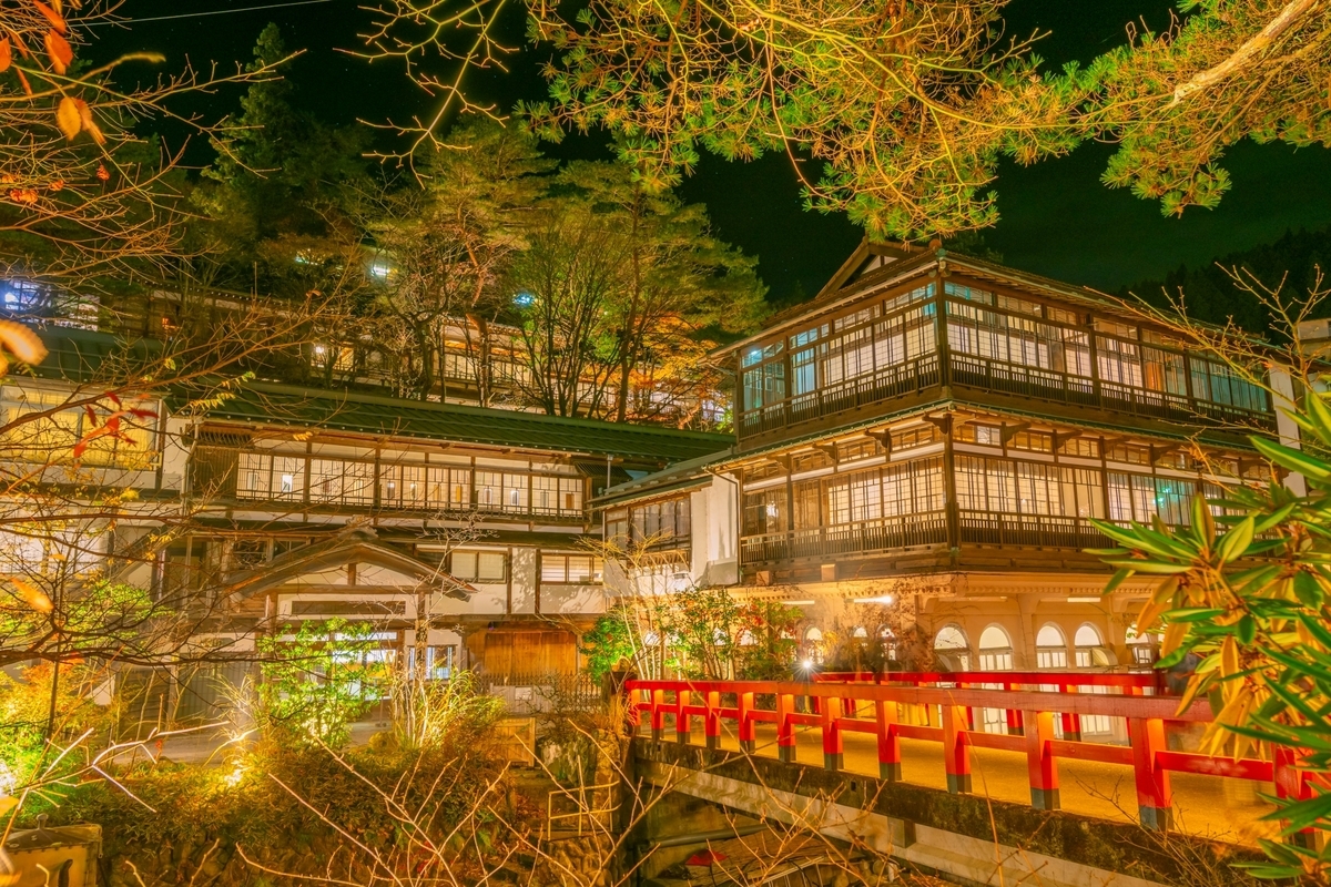 Los ryokan de madera y el puente rojo de Shima Onsen iluminados de noche