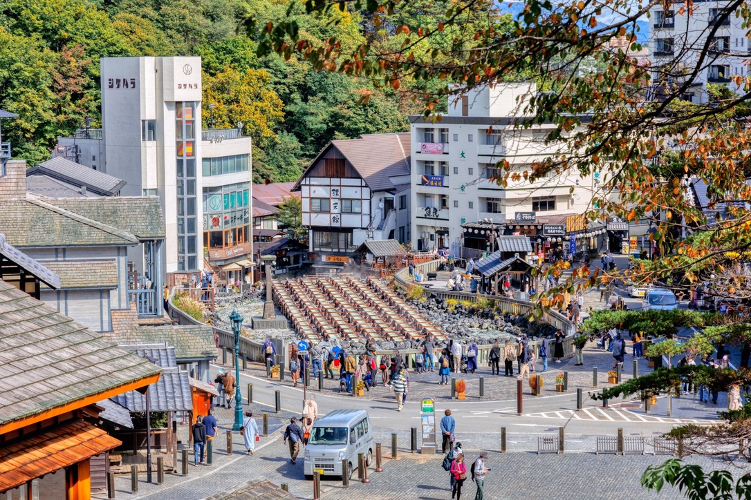 El yubatake de Kusatsu Onsen bullicioso de visitantes y el pueblo termal circundante