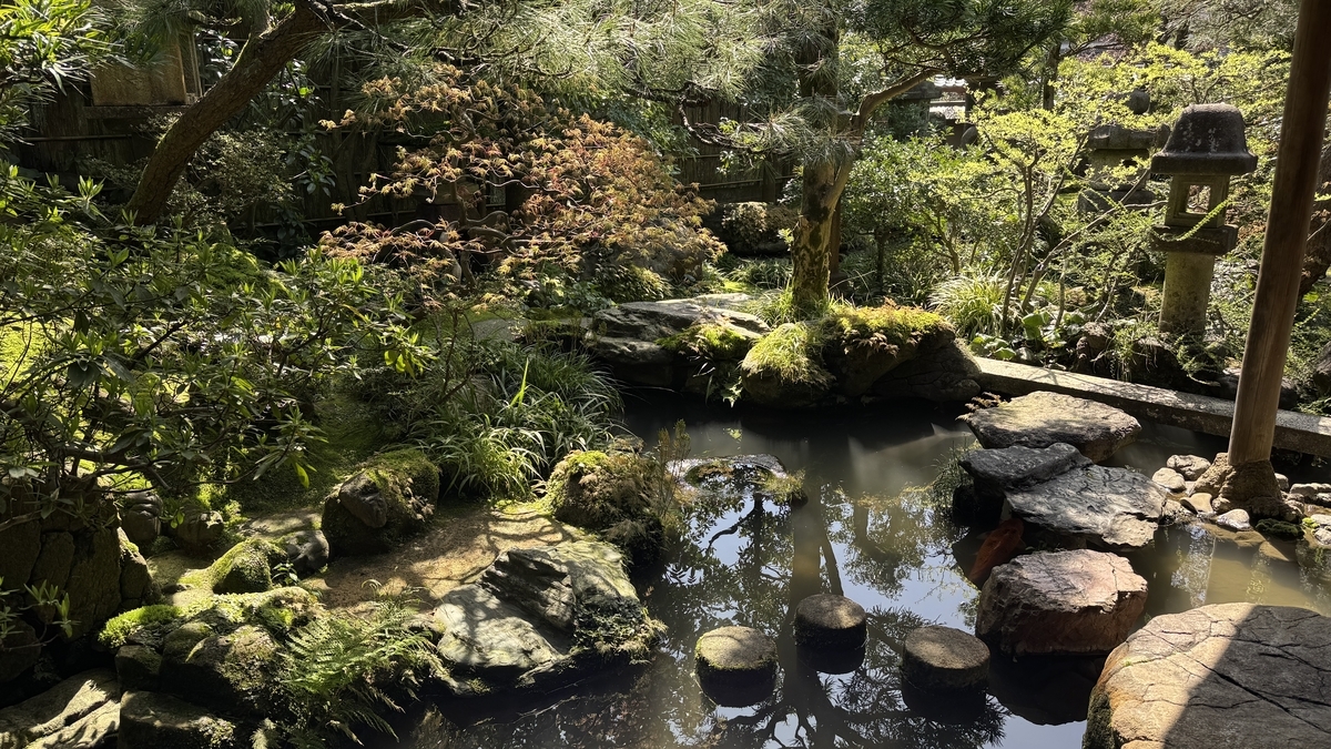 池のように広がる曲水と庭木に囲まれた野村家の庭園