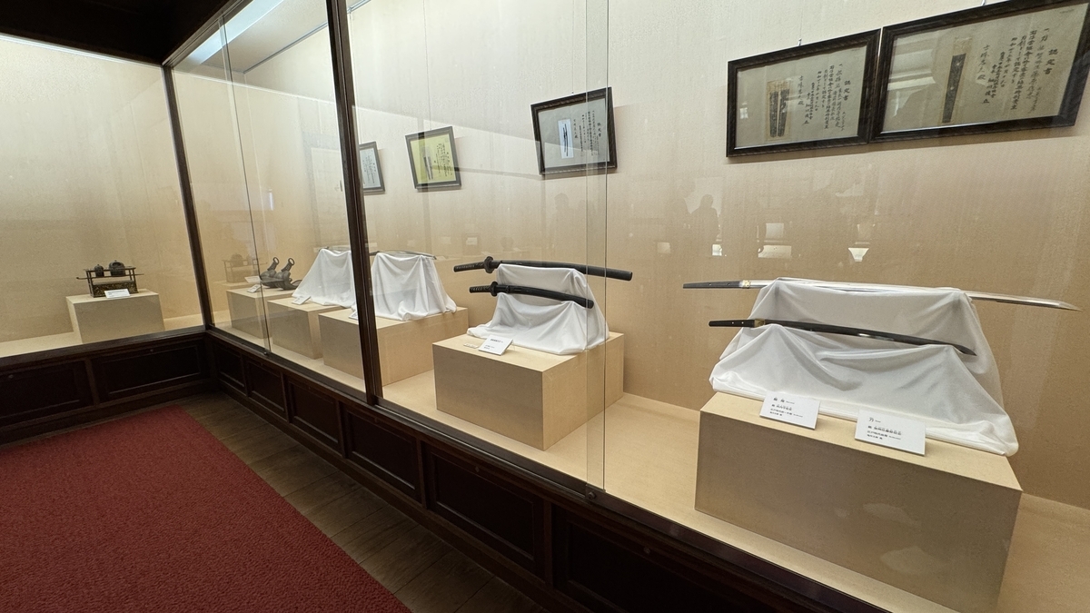 鬼川文庫のガラスケースに並ぶ刀剣と書状の展示