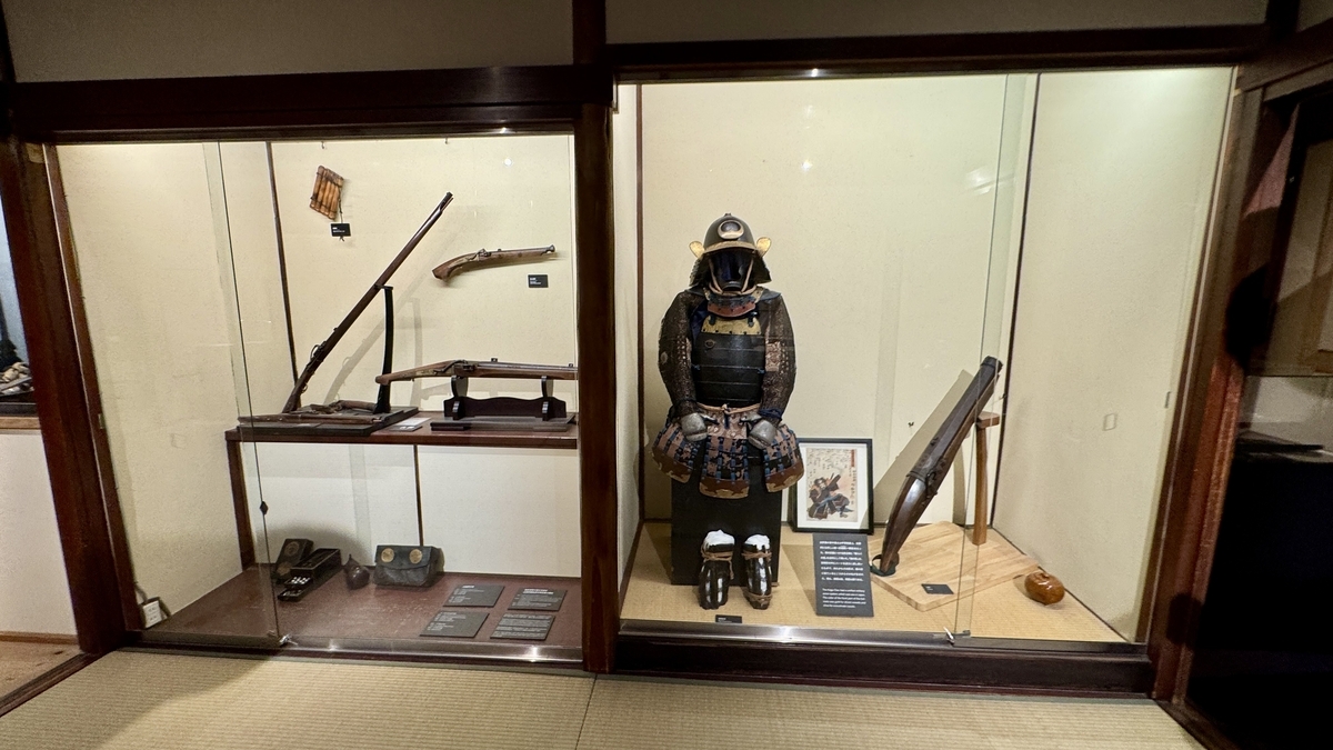 A glass case displaying matchlock guns and armor
