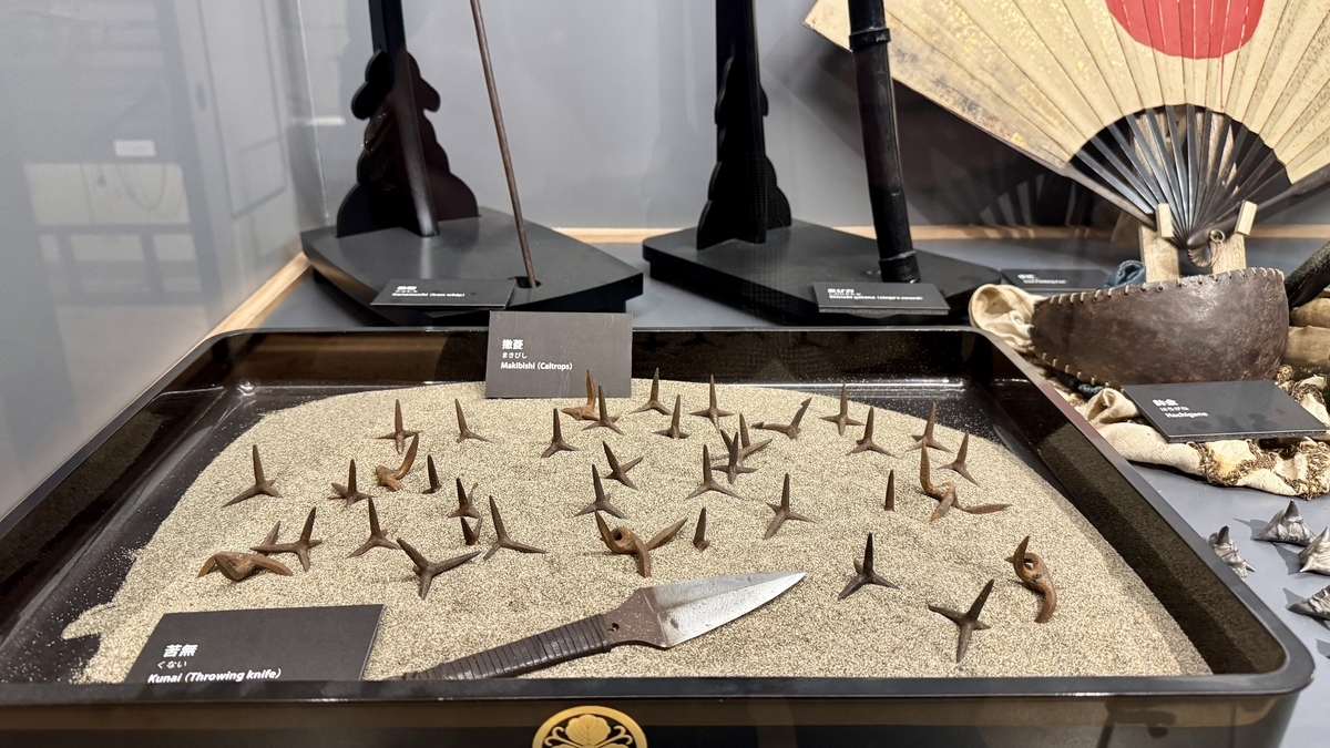 A display of caltrops and kunai set on sand