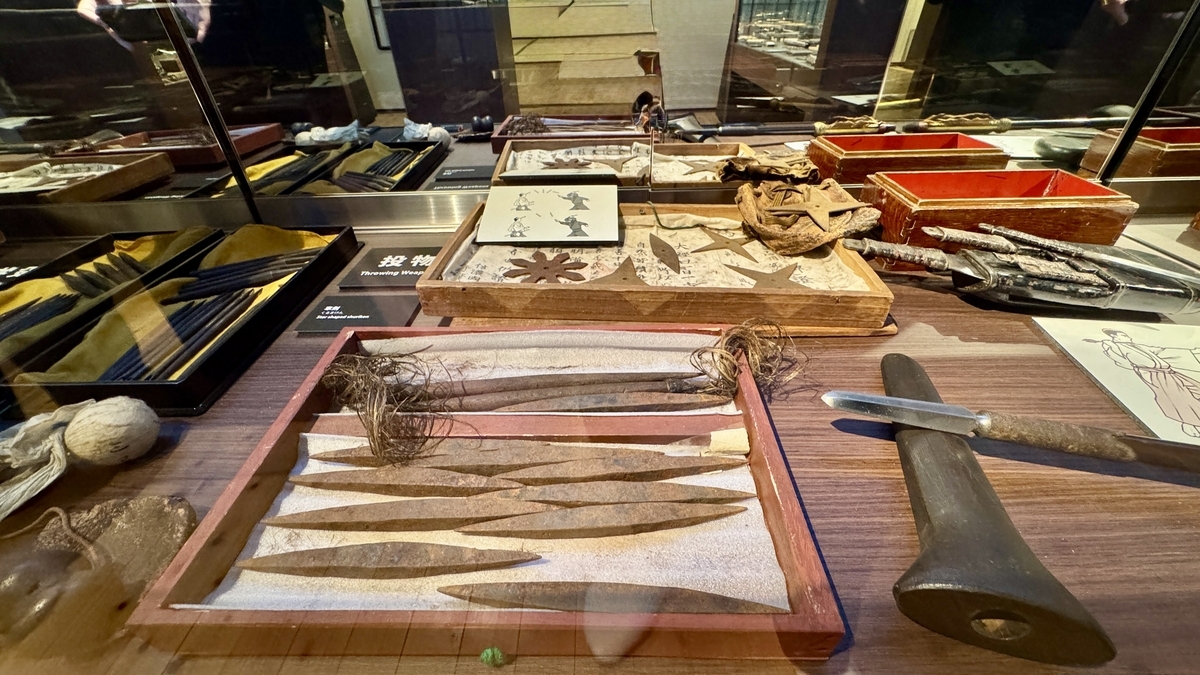 A display of throwing darts, shuriken, and blowgun tubes