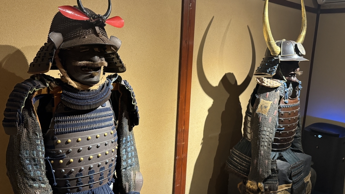 Two suits of armor and helmet crests seen up close