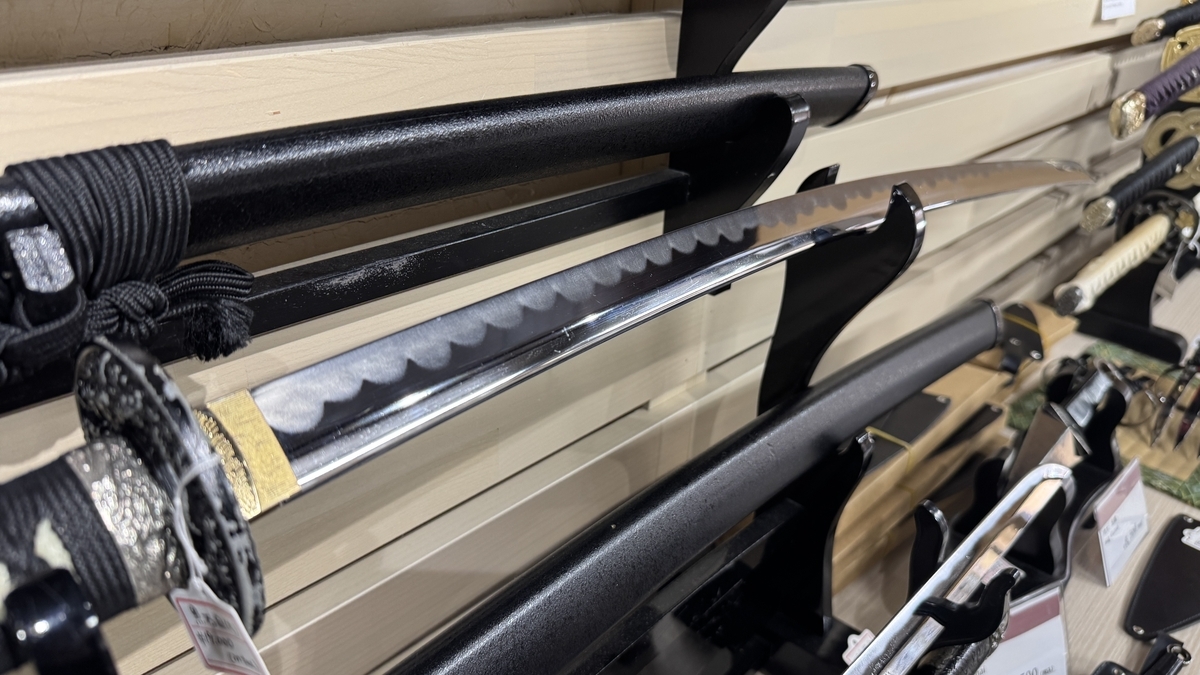 A close-up of a replica katana blade drawn from its scabbard