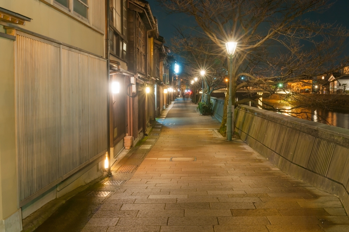 Riverside stone pavement lit by the glow of machiya at night in Kazuemachi Chaya District