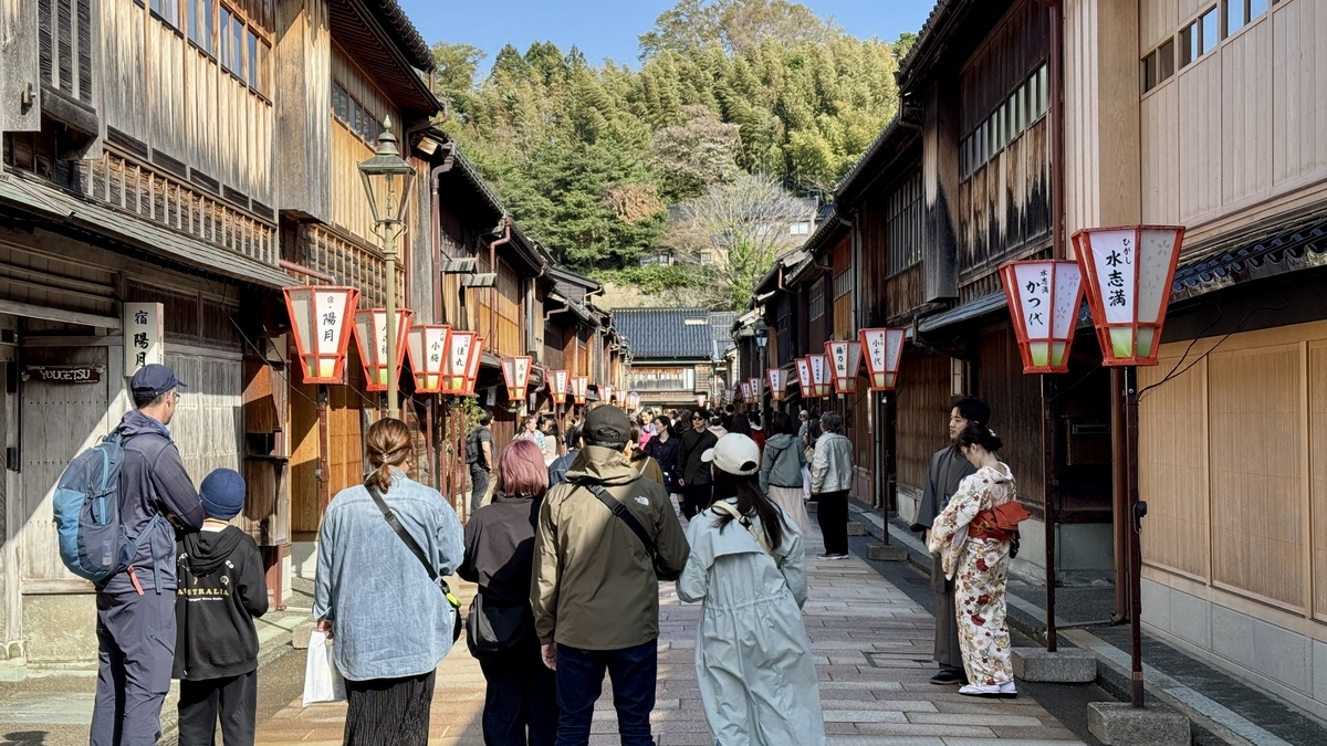 Turistas y personas en kimono paseando por el barrio Higashi Chaya bordeado de farolillos