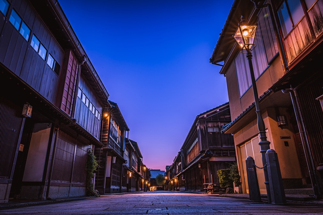 Una calle del barrio Higashi Chaya iluminada por farolas bajo un cielo azul del atardecer