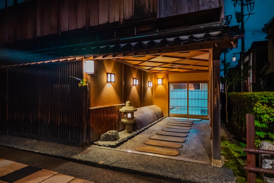 La entrada de una casa de té y una linterna de piedra iluminadas de noche