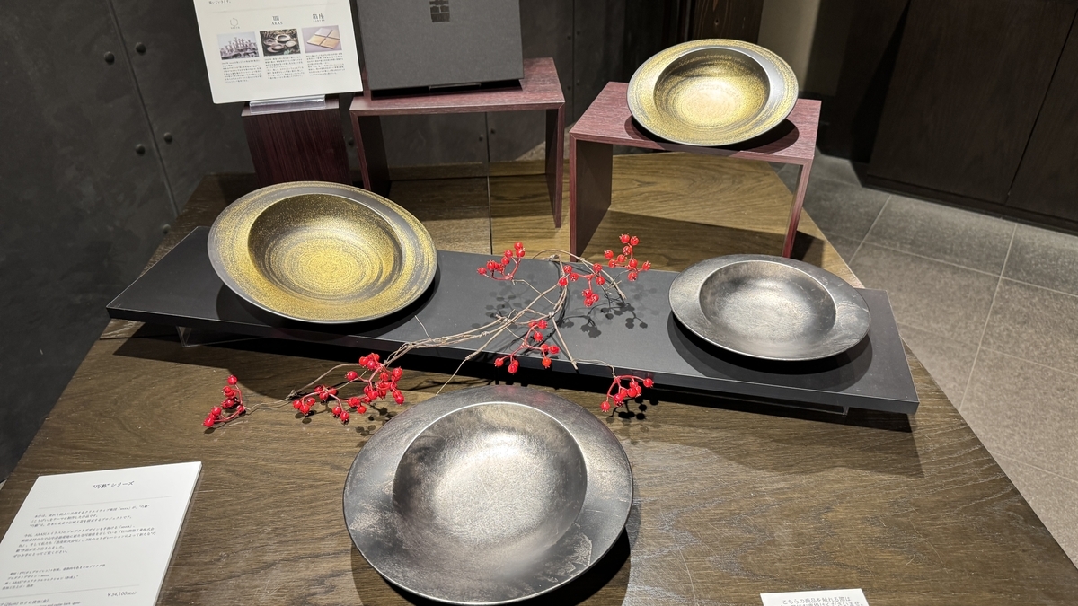 Un gran plato reluciente en negro y dorado expuesto en Hakuza Hikarikura