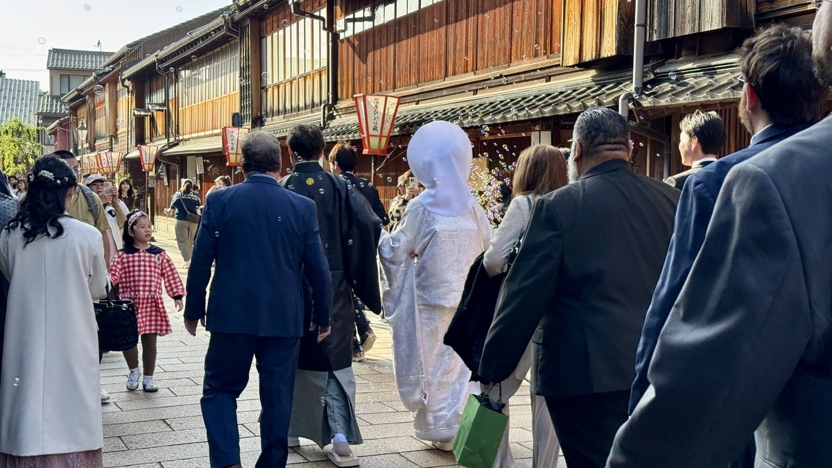 Una novia con shiromuku avanzando por el barrio Higashi Chaya en un cortejo nupcial