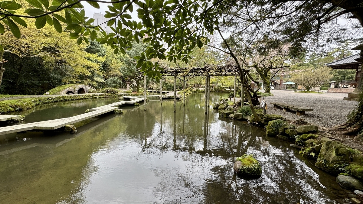 尾山神社神苑的水池與倒映水面的紫藤棚
