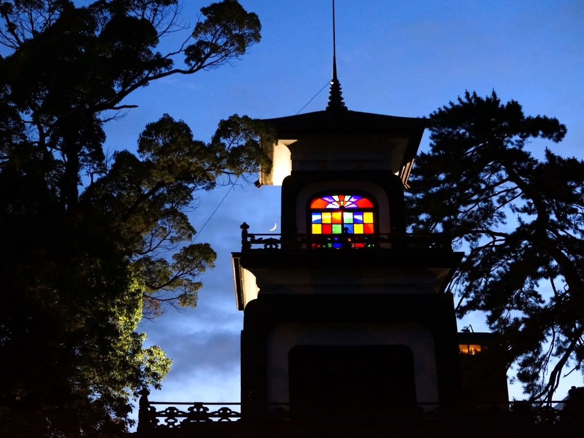 暮色中尾山神社神門上閃耀的彩色玻璃與新月